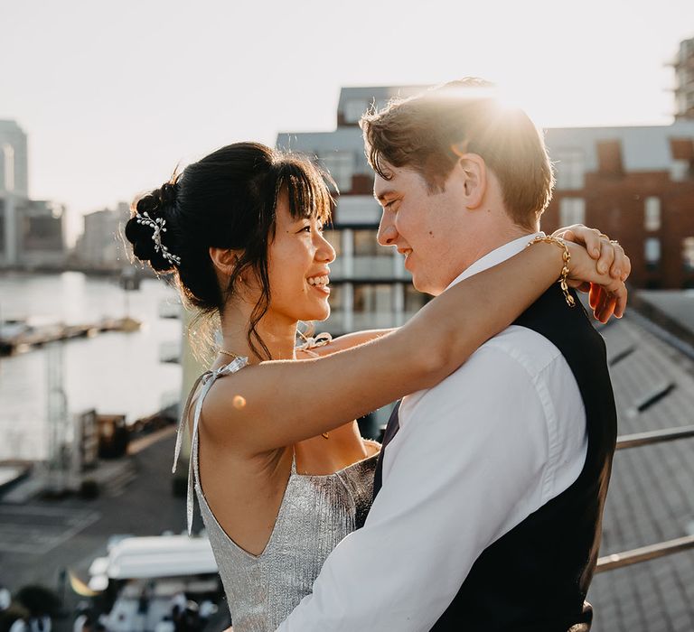 East Asian bride kisses her groom at Trinity Buoy Wharf lighthouse during golden hour 