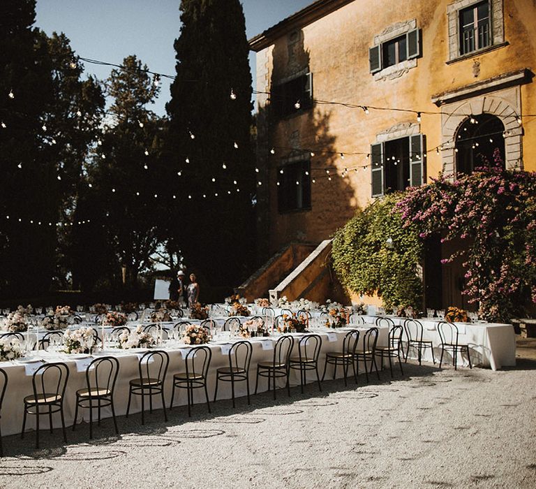 Banquet tables for outdoor wedding ceremony in Tuscany complete with hanging festoon lighting 