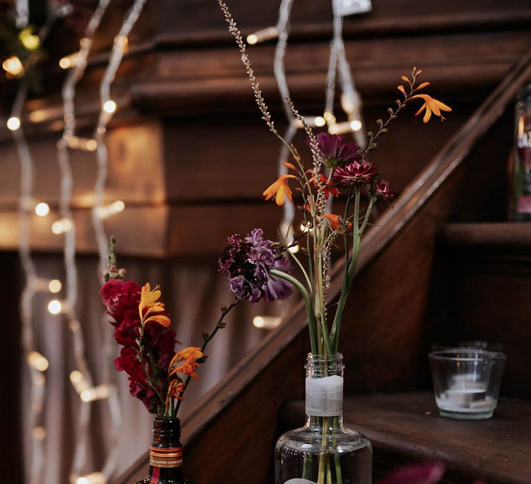 string lights, wildflower stems in liquor bottles and disco balls decorating the wedding venue 