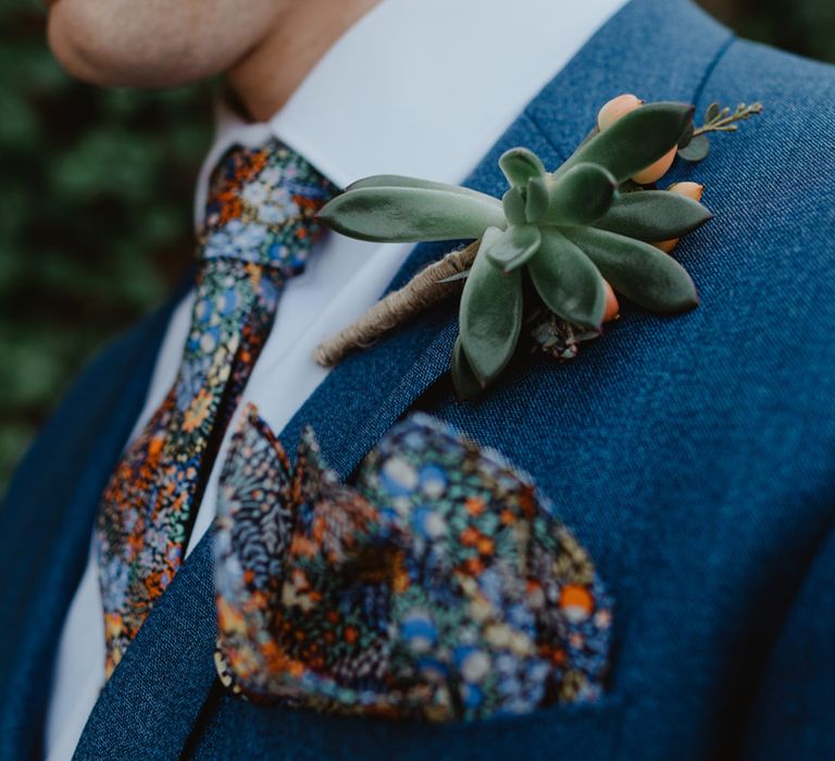 Bride in blue suit with colourful floral tie and pocket square for fun barn wedding 