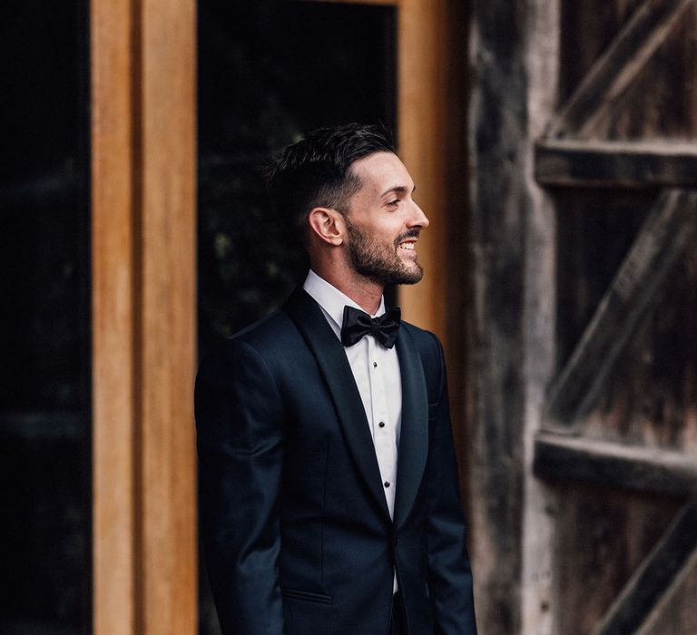 The groom in a traditional tuxedo and black tie for the barn wedding 