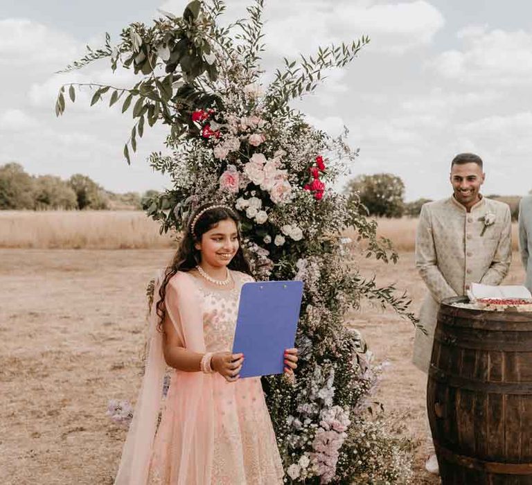 Young wedding guest in baby pink tulle dress with rose gold embellishments doing wedding speech at Gujarati wedding ceremony at High Billinghurst Farm wedding venue 