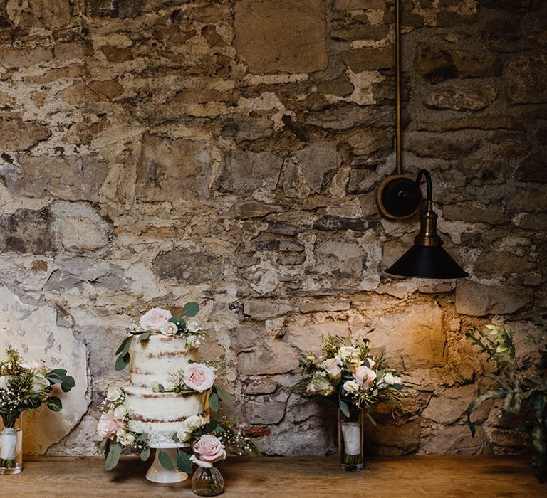 Two tier rustic semi-naked wedding cake decorated with pink roses and gypsophila 