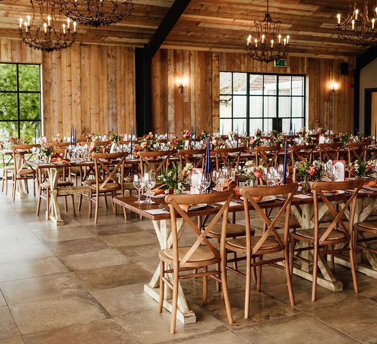 Tall blue taper candles with copper taper candles and napkins for the autumn wedding at the barn with chandeliers overhead 