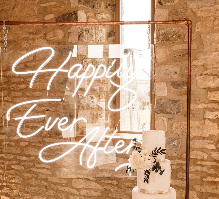 Happily ever after white neon wedding sign and wedding cake with ribbon and brooch decoration