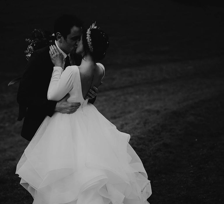 Bride in ruffle layered wedding dress kissing groom