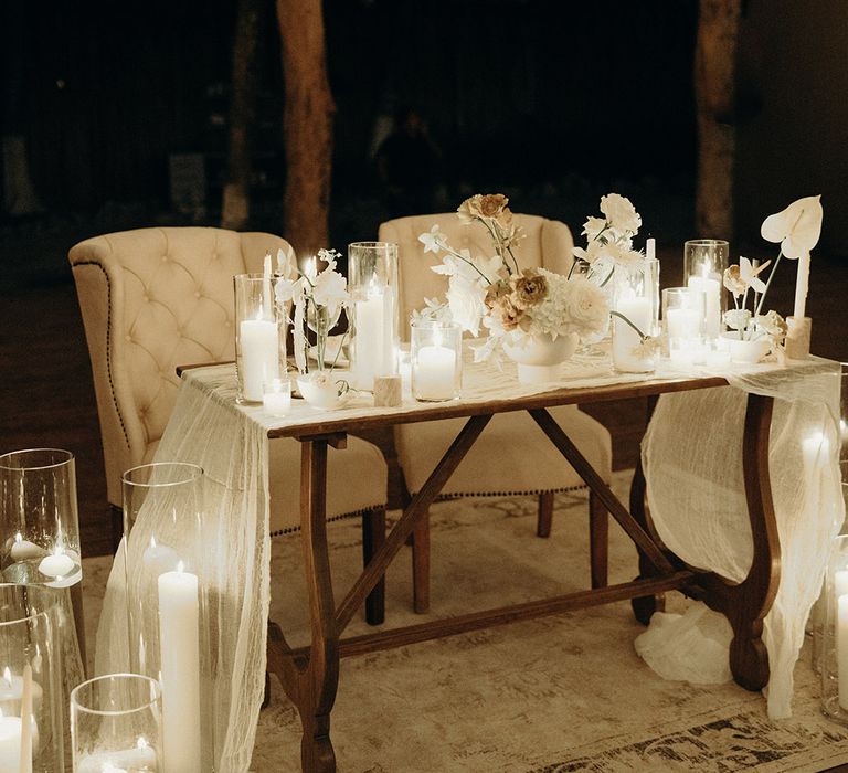 sweetheart table with white chairs, modern wedding flowers and candle table decorations