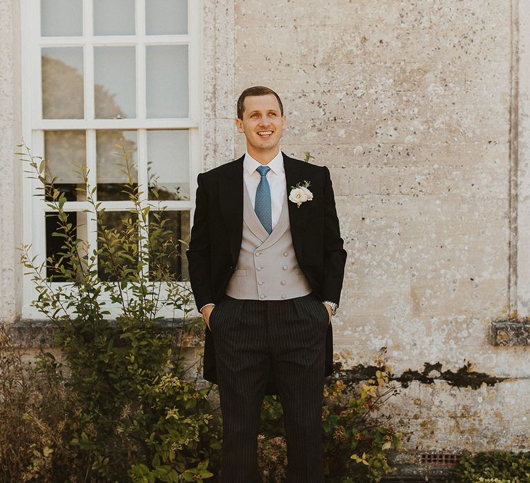 Groom in morning suit with dark suit jacket, striped trousers, light blue tie and white flower buttonhole for traditional wedding | Steph Newton Photography