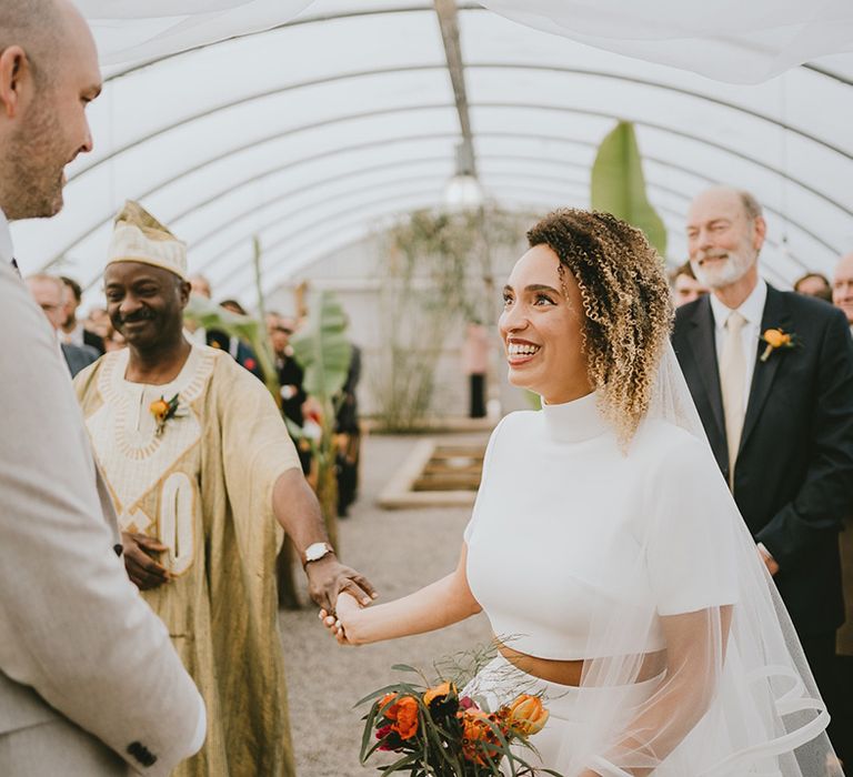 Groom in a cream suit greets the bride in Jesus Peiro trousers and top bridal set meeting each other 