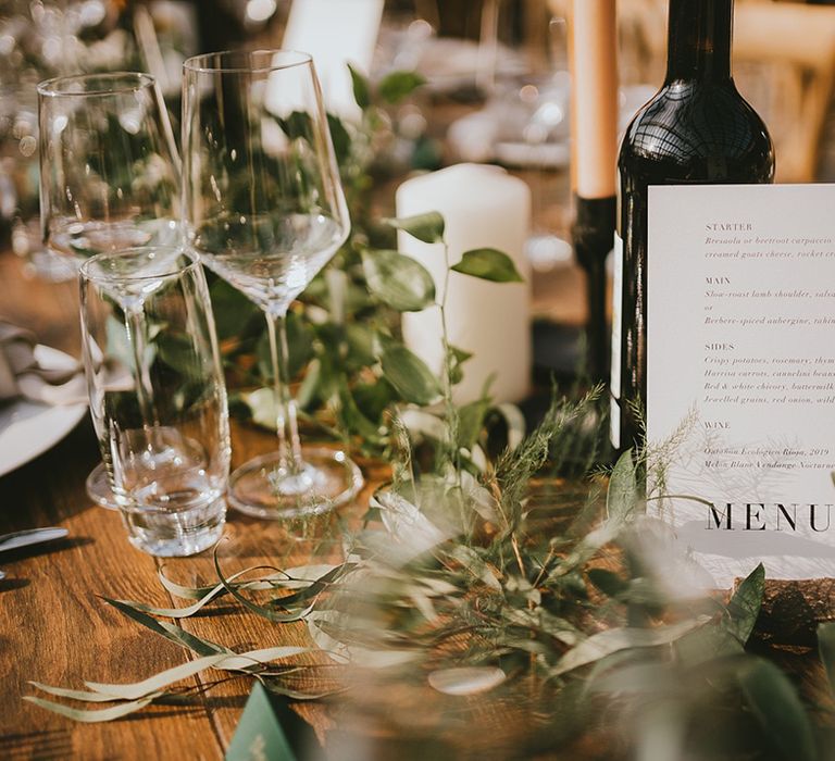 Black and white simple wedding menu sign surrounded by neutral wedding taper candles and foliage for botanical wedding 