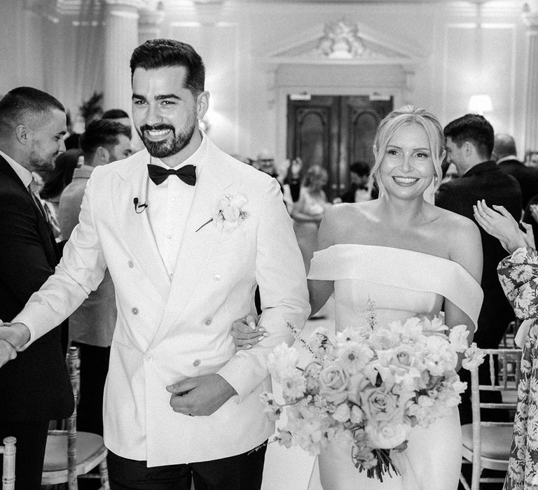 The bride and groom walk back down the aisle after their ceremony 