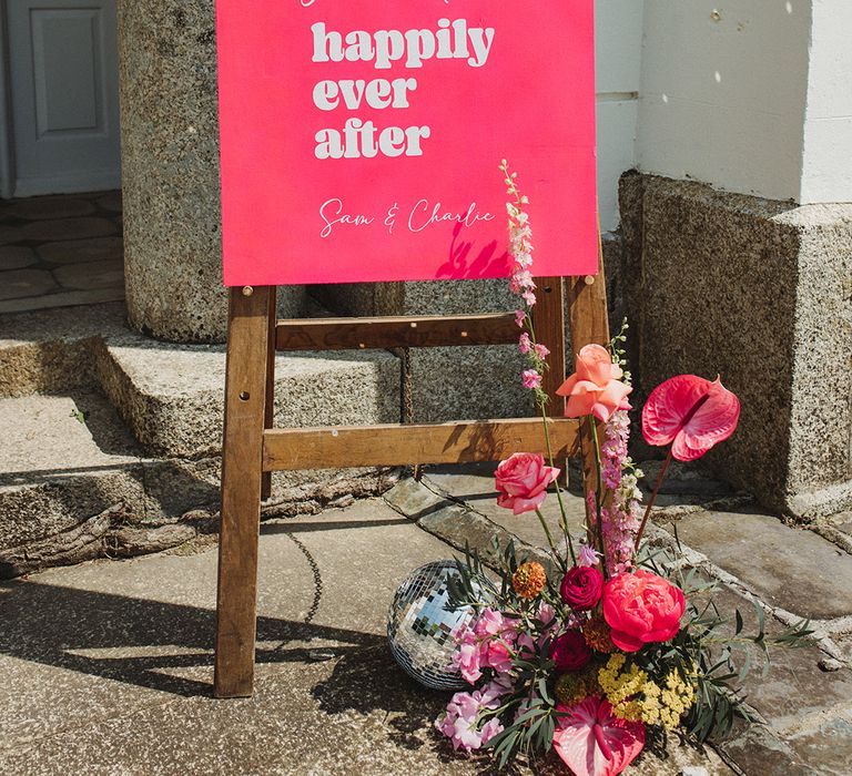 Bright hot pink neon wedding welcome sign with pink wedding flower arrangements with anthuriums and disco balls 