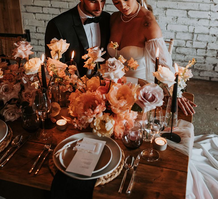 Bride in strapless wedding dress with pearl wedding jewellery and hair ribbon with groom in black tuxedo at Eden Barn wedding 