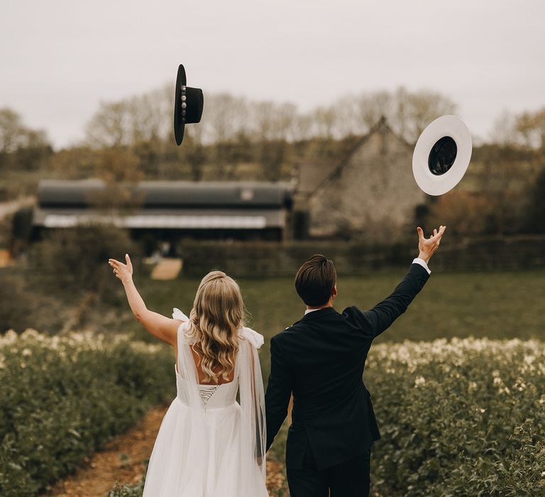 The bride and groom throw their cowboy hats in the air at Stone Barn rustic wedding venue 