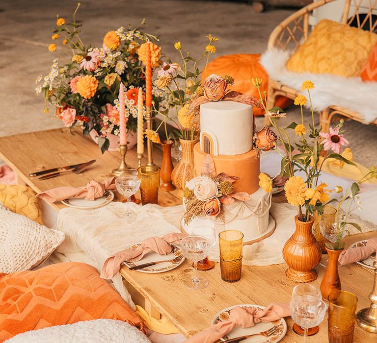 Themed wedding tablescape with orange wedding flowers, decorations and wedding cake 