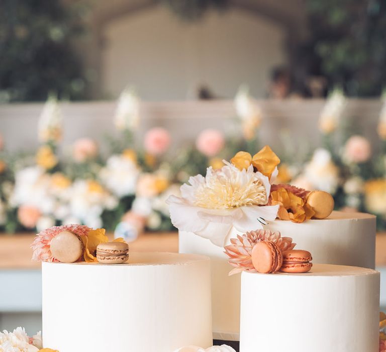 Three single tier wedding cakes with orange macaron and flower decor