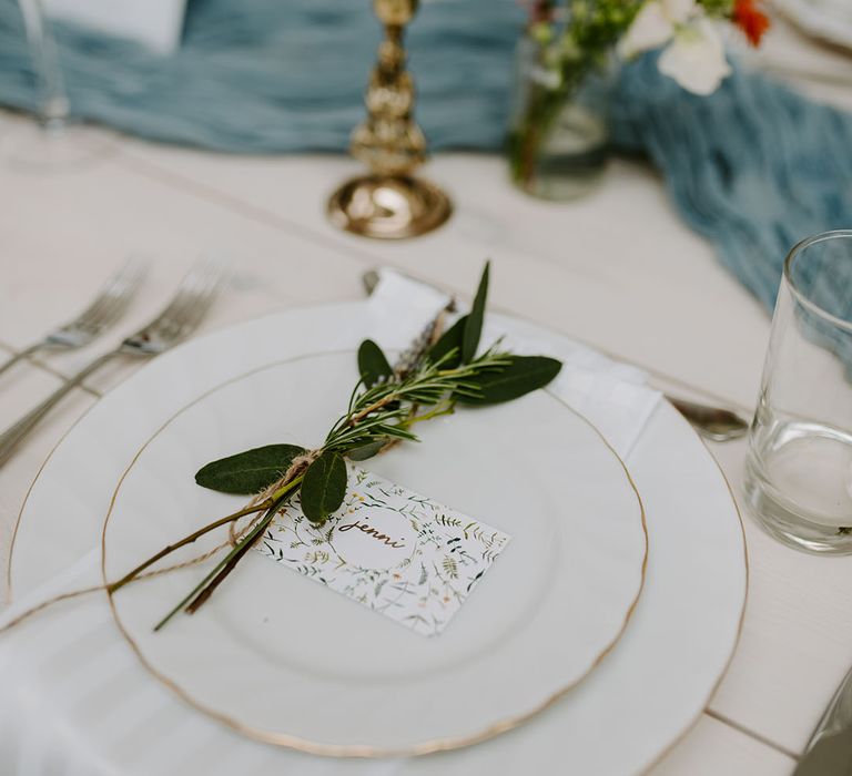 Wedding place setting with white plates, DIY wedding place name and sprig of herbs 