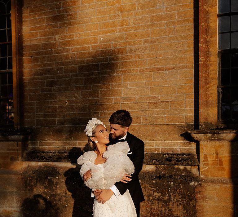 Bride in short wedding reception dress with pearls and puff sleeves with the groom in a black tuxedo at Minterne House 