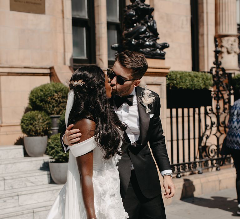 Bride in off the shoulder wedding dress kissing the groom 