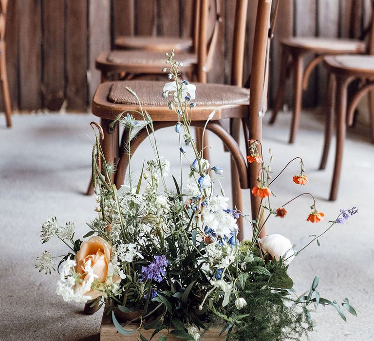 Rustic barn wedding with wedding aisle flowers in wooden crate boxes with orange, purple, and blue flowers