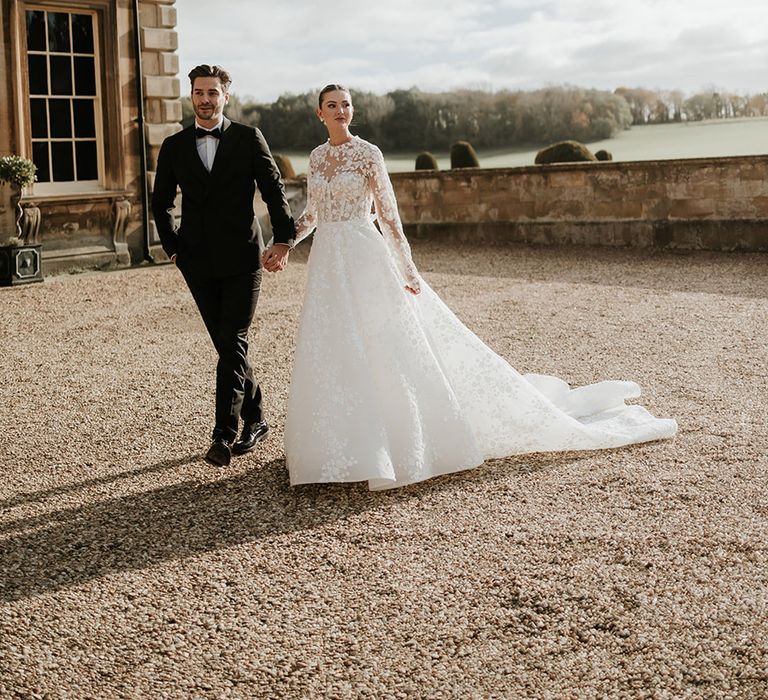 bride in long sleeve wedding dress walking with the groom at Prestwold Hall 