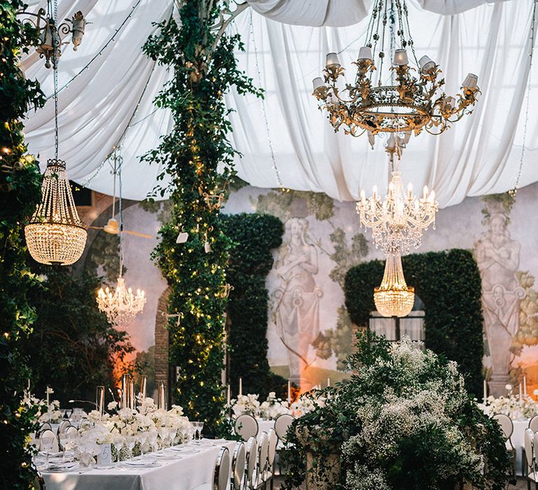 White wedding theme with foliage and chandeliers decorate the wedding venue 