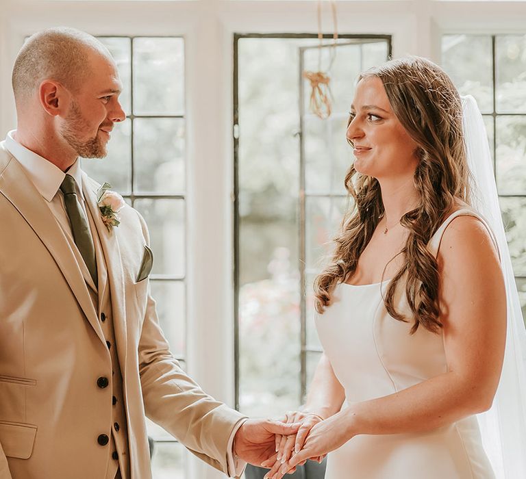 Registry office wedding ceremony with bride and groom holding hands 