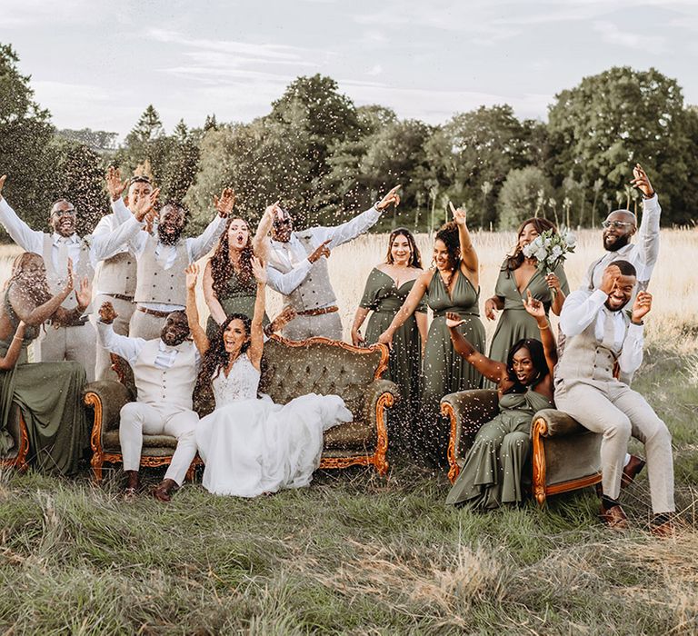 Champagne spray wedding photo with the bridesmaids in green bridesmaid dresses and groomsmen in cream wedding suits