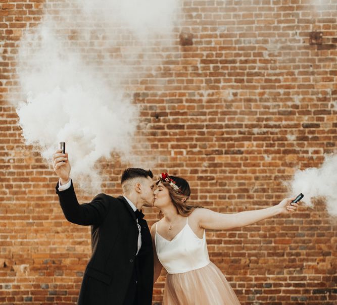 Newly married couple kissing with smoke bombs