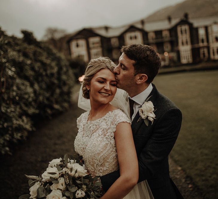 Groom kissing his new wife at picturesque winter wedding in the Lake District 