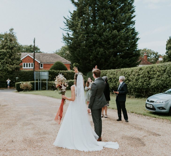 Bride and groom waving to passers by in the village 