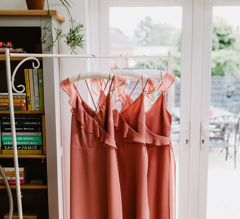 Pink satin bridesmaids dresses hung up 