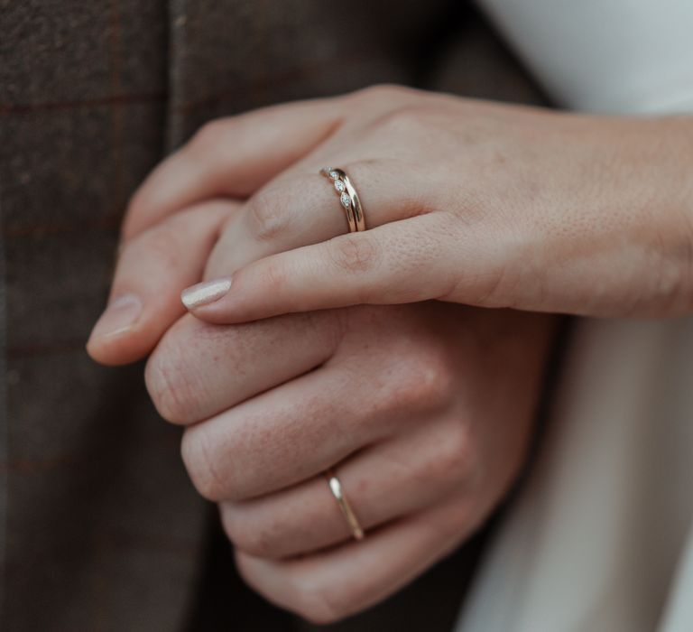 Bride & groom hold hands with wedding bands showing