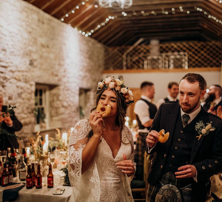 Boho bride eating a doughnut from doughnut wedding cake at highland wedding in Glencoe