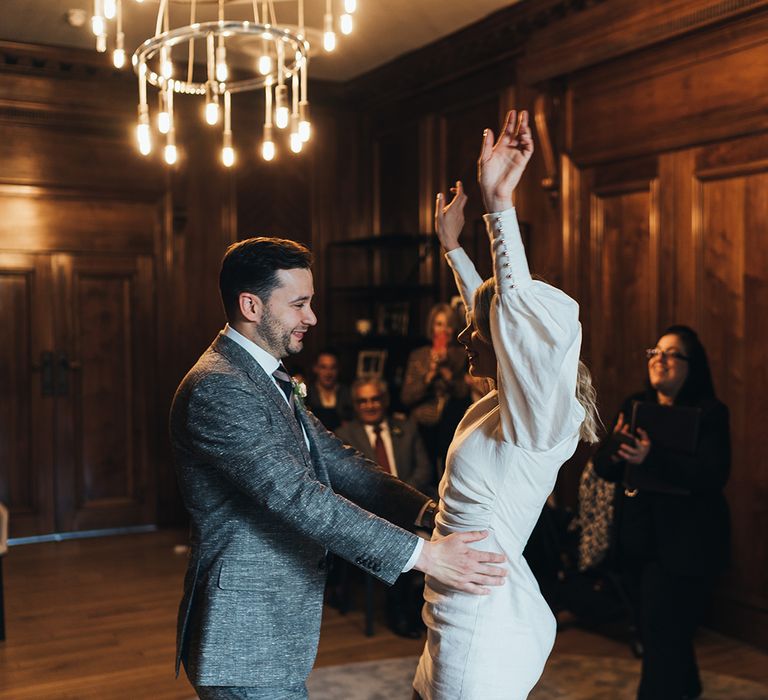 Newly wed bride and groom with bride raising her arms in celebration and groom holding his new bride at town hall wedding 