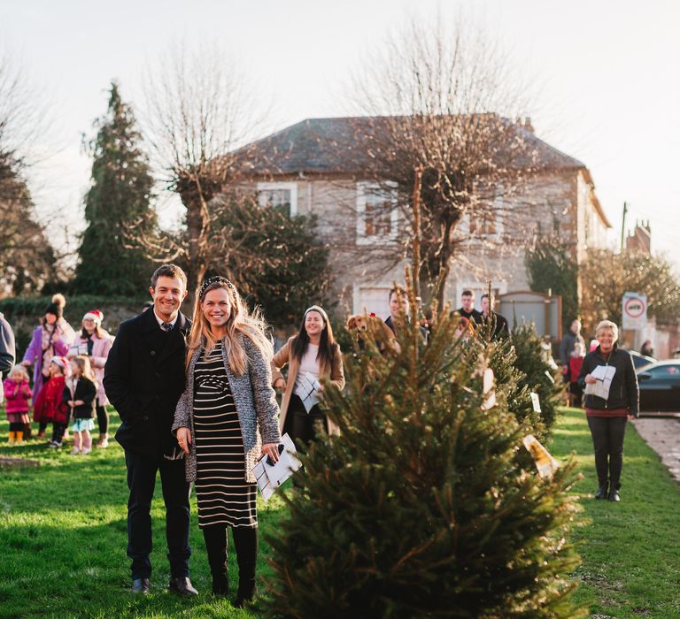 Wedding guests stand socially distanced outdoors for bride & groom