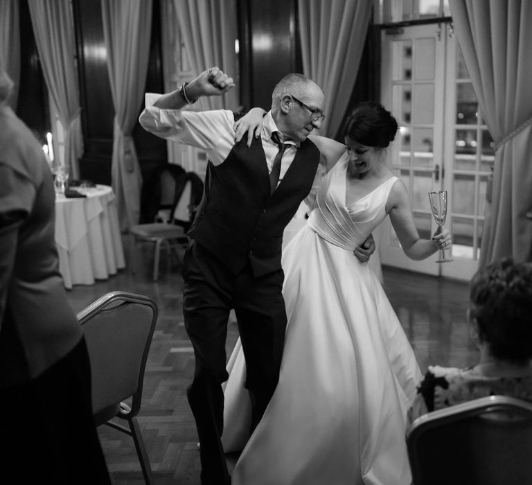 Bride dancing with wedding guest holding champagne