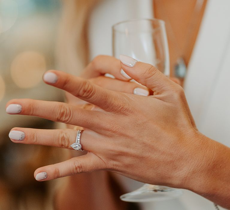 Brides hands with diamond engagement ring and neutral nail colour complete with glitter