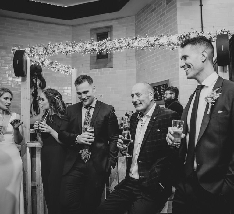 Wedding guests gather in black & white image for evening reception