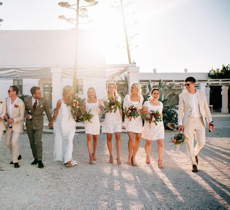 The bride, groom and wedding party walking together in the afternoon sun