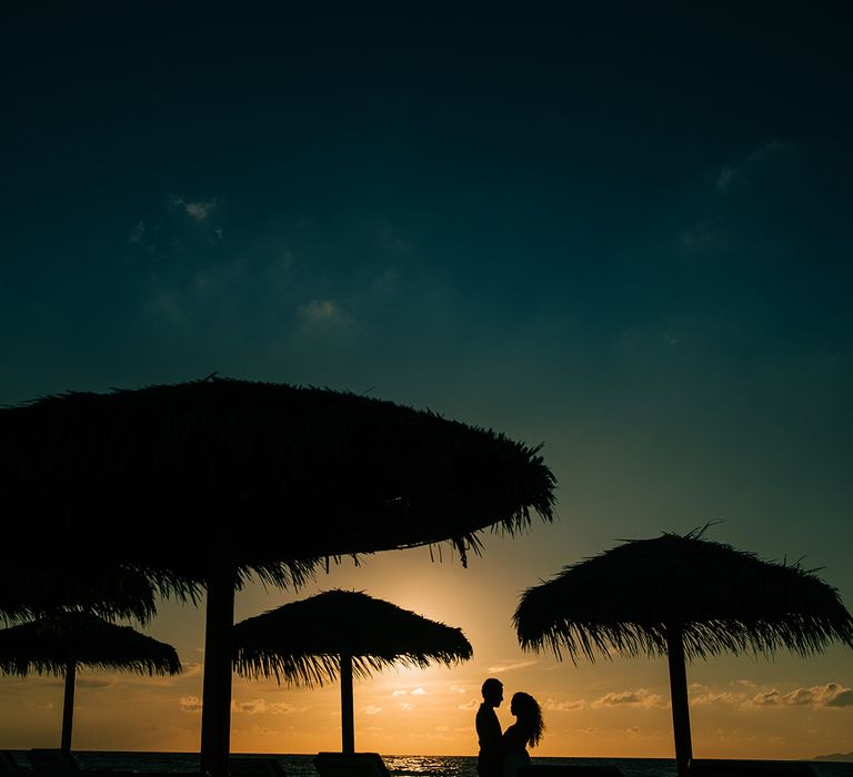 Bride & groom stand on the beach 