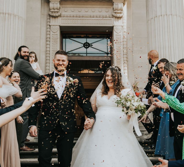 Bride & groom walk down the steps of Old Marylebone Town Hall as confetti is throw around them 