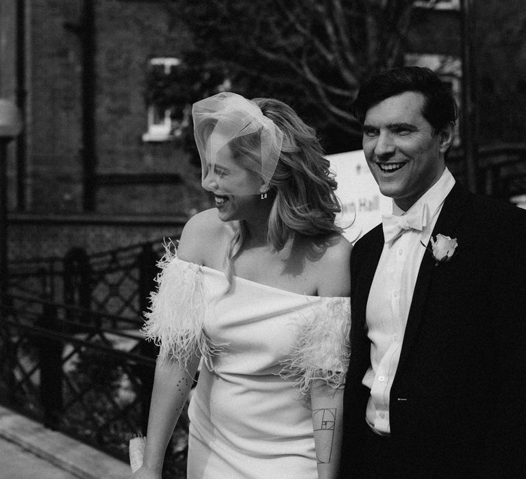 Black and white wedding day photography - bride wears off the shoulder wedding dress with feather detail 