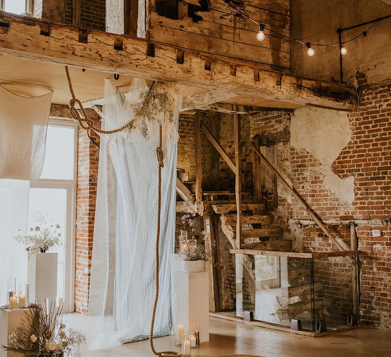 Godwick Great Hall and Barn wedding ceremony decor with drapes, ropes, rugs and dried flowers 