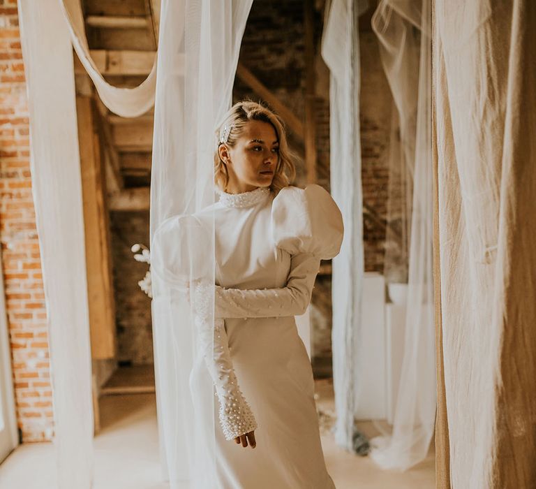 Bride in a fitted wedding dress with pearl studded sleeves and puff shoulder detail 