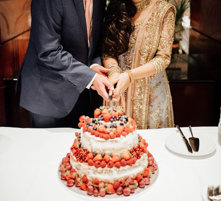 Bride & groom cut wedding cake during wedding reception