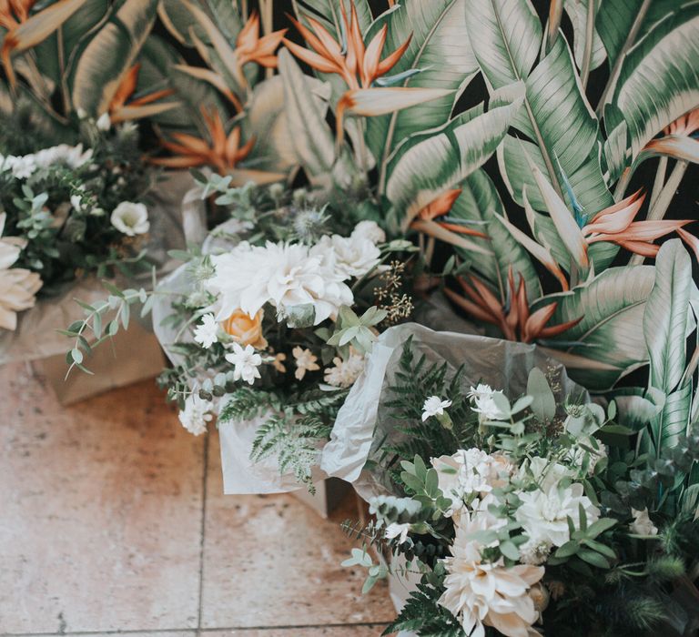 Dahlia bouquets sit in gift bags at a wedding. 