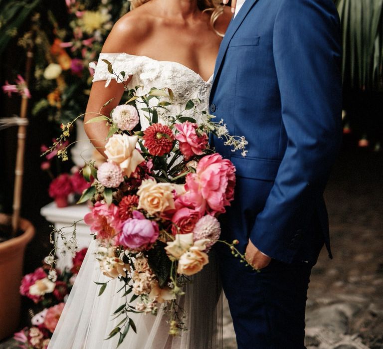 Bride and groom hugging at their finca wedding in Spain, holding a large pink bouquet