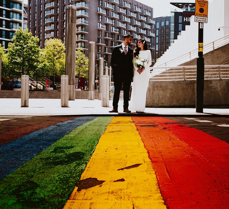 Bride and groom standing next to a rainbow crossing in Brent, London 