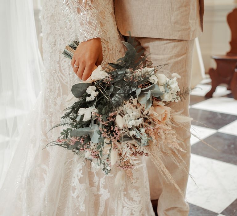 Bride holds pastel bouquet filled with roses and green foliage